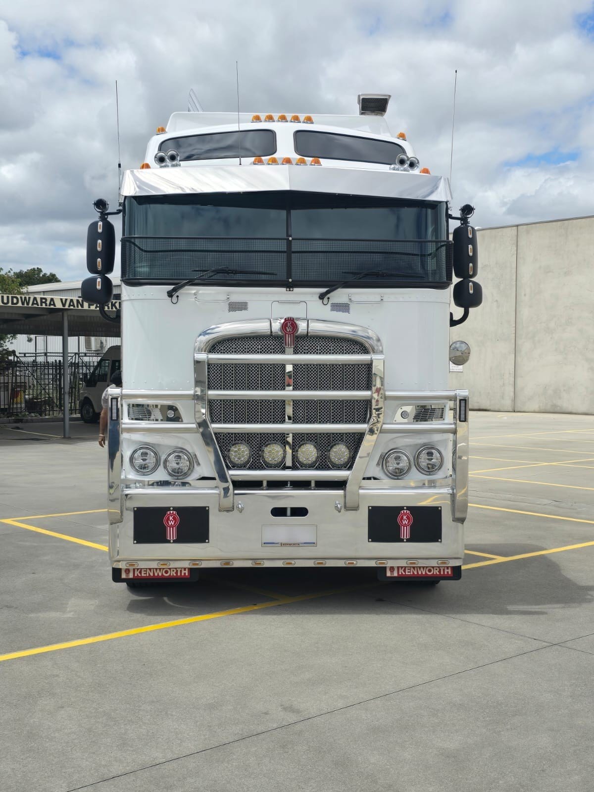 White Kenworth prime mover, front on, parked in a depot yard